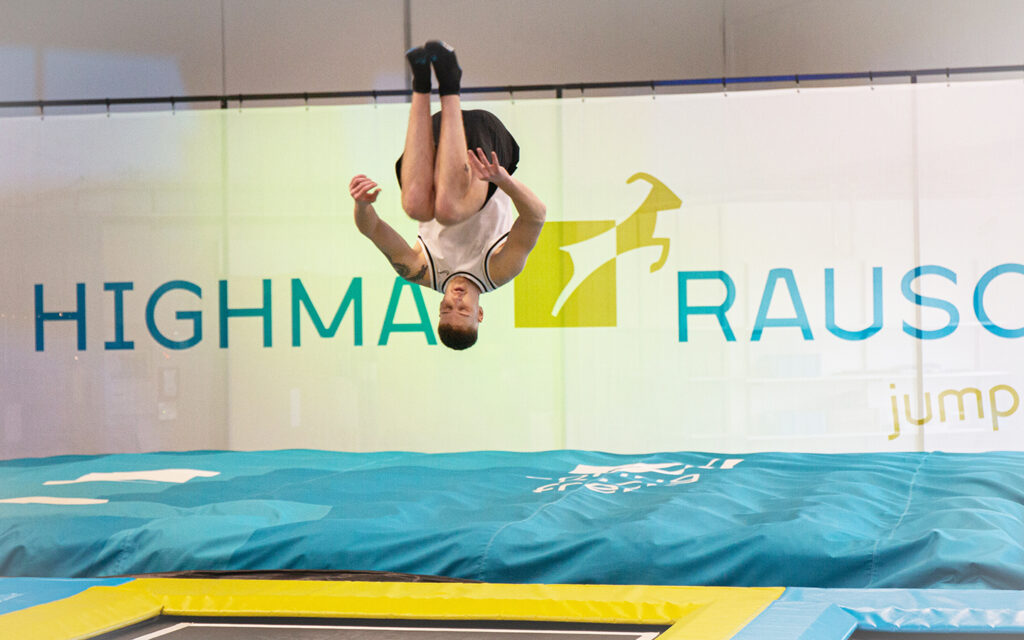 Junger Mann macht in der Trampolinhalle auf dem Trampolin einen Salto-Sprung