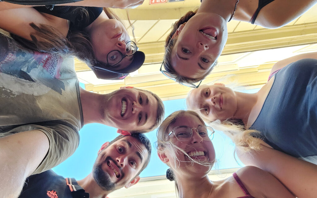 Jugendliche stecken ihre Köpfe zusammen und schauen von oben herab in die Kamera