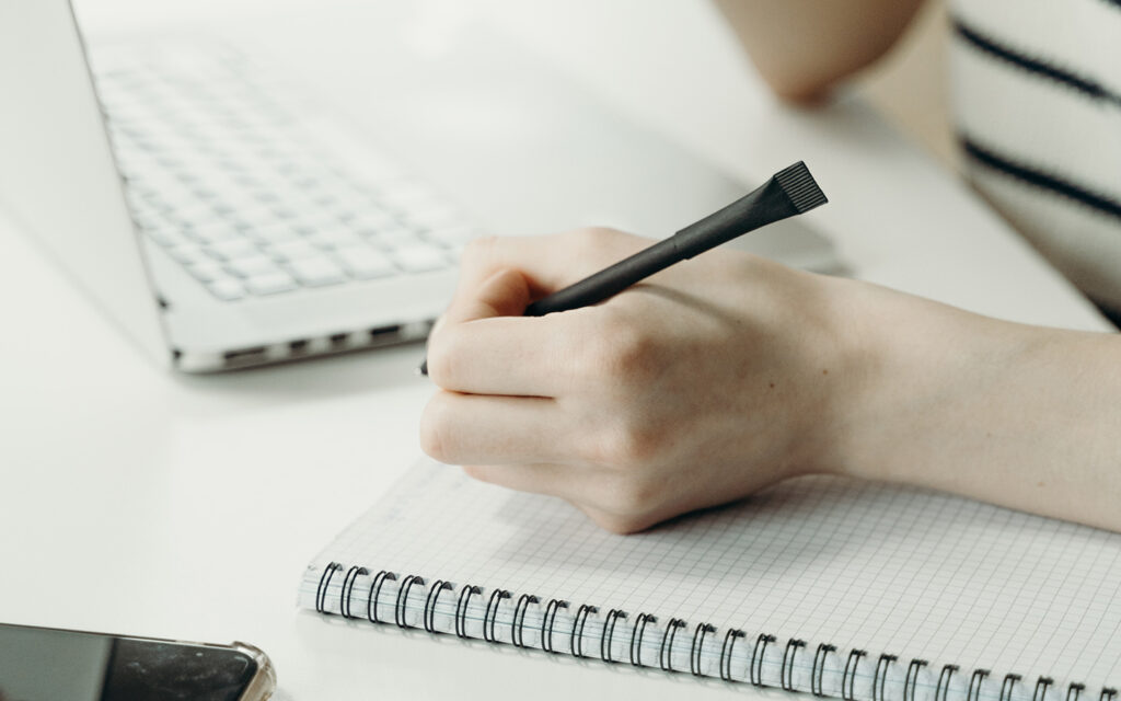 Ein Mädchen schreibt sich auf einen Block etwas auf