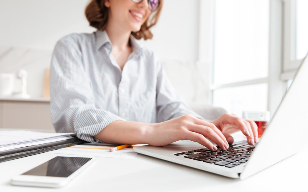 Junge Frau arbeitet an ihrem Laptop und lacht