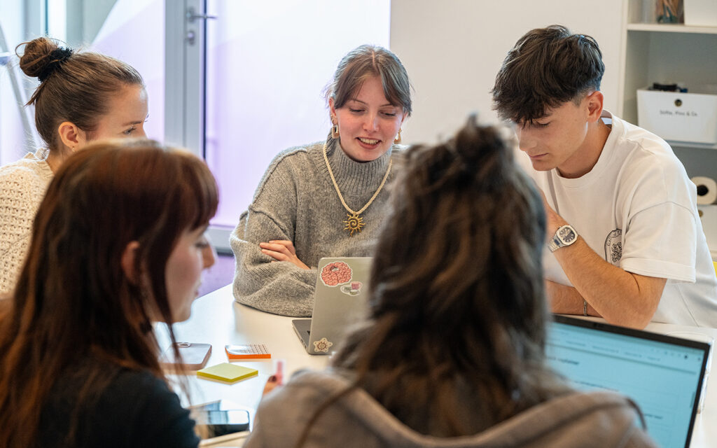 Junge Menschen sitzen in einer Workshopsituation rund um einen Laptop.