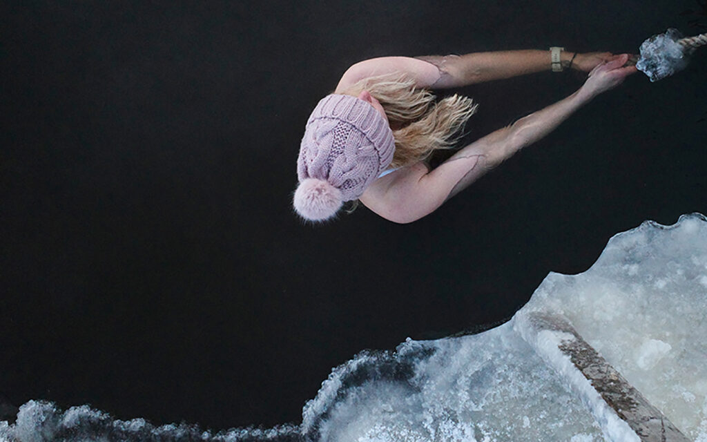 Eine junge Frau badet im Winter im See