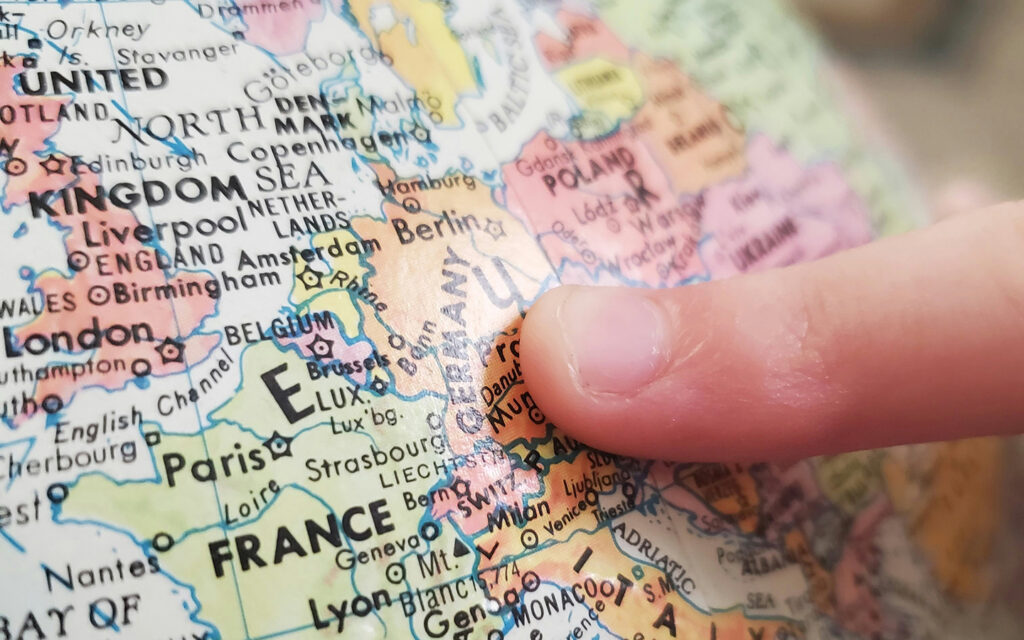 Man sieht, wie jemand mit seinem Finger auf Europa auf einem Globus zeigt