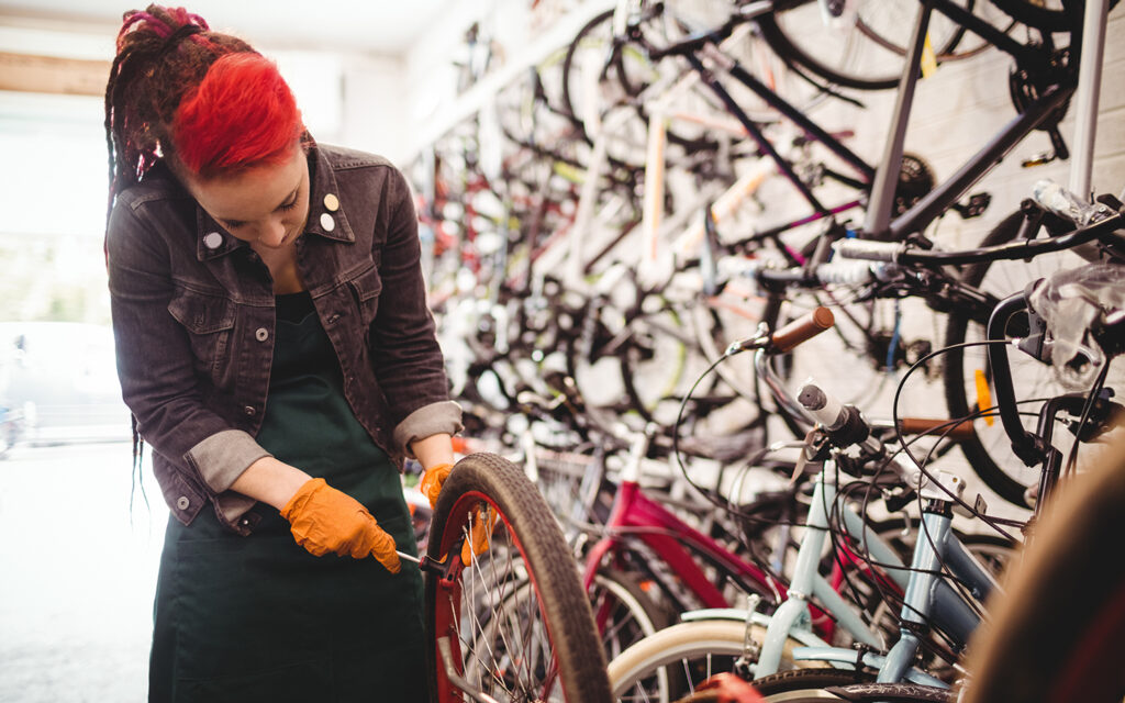 Eine Frau mit repariert in einer Fahrradwerkstatt professionell die Räder