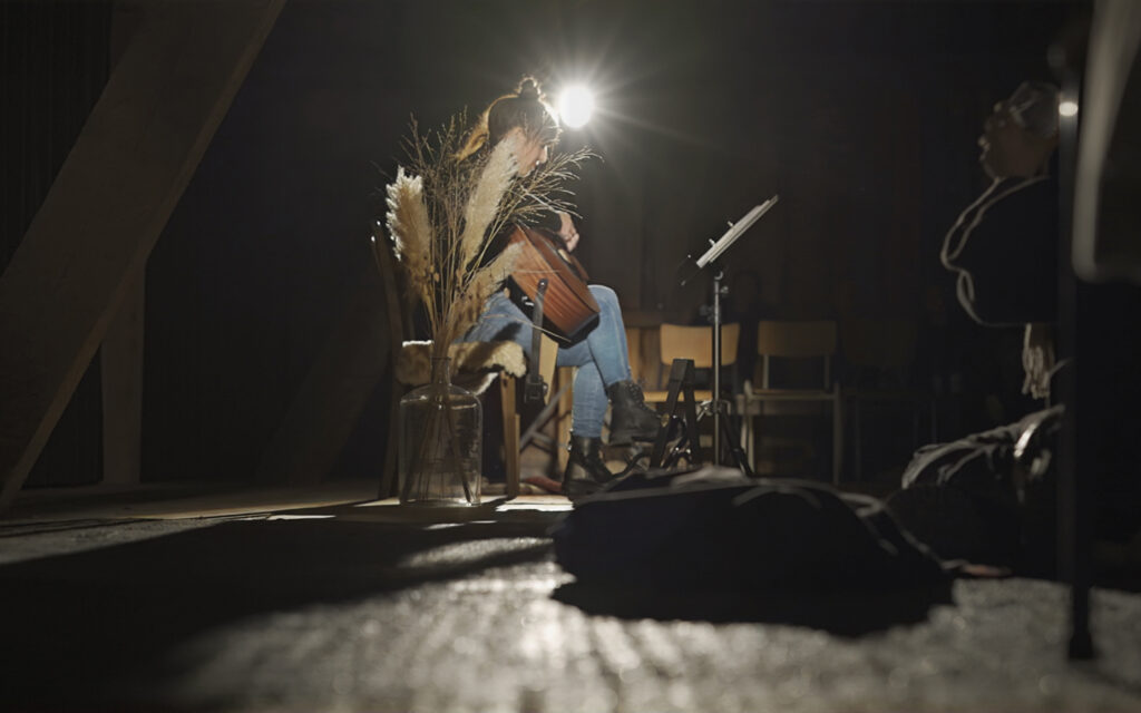 Eine Gitarrenspielerin sitzt mit ihrer Gitarre auf der B&uuml;hne und spielt