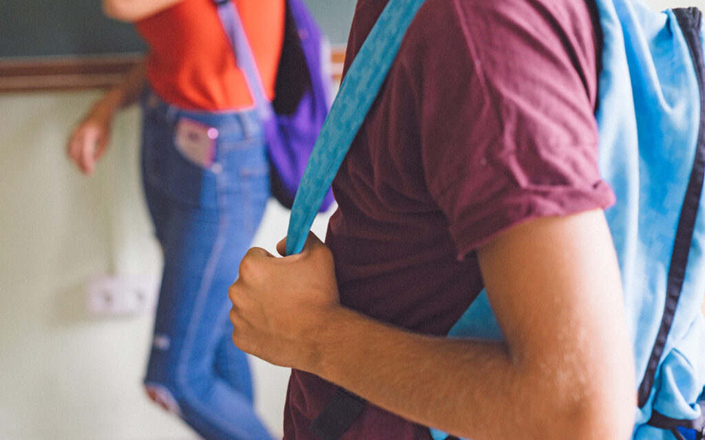 Junge in der Schule im Gang mit seinem Schulrucksack