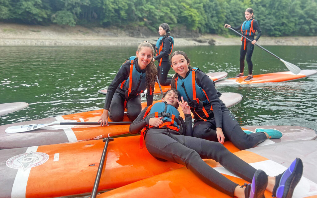 Drei M&auml;dels posieren auf Kajak-Booten und haben Spa&szlig;
