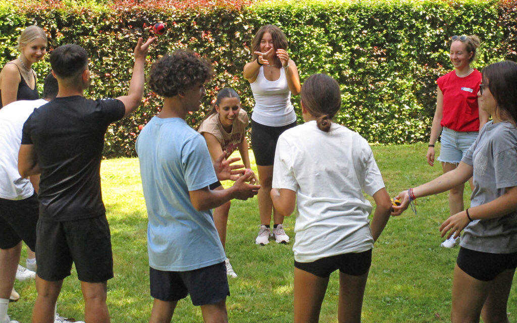 Jugendliche spielen miteinander drau&szlig;en Ball
