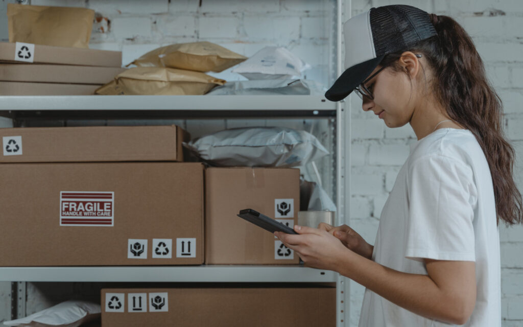 Eine junge Frau checkt die Pakete in einem Lager.