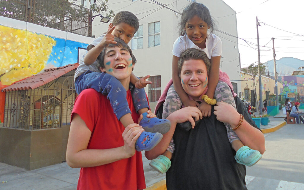 Junge Auslandszivildiener tragen Kinder auf ihren Schultern