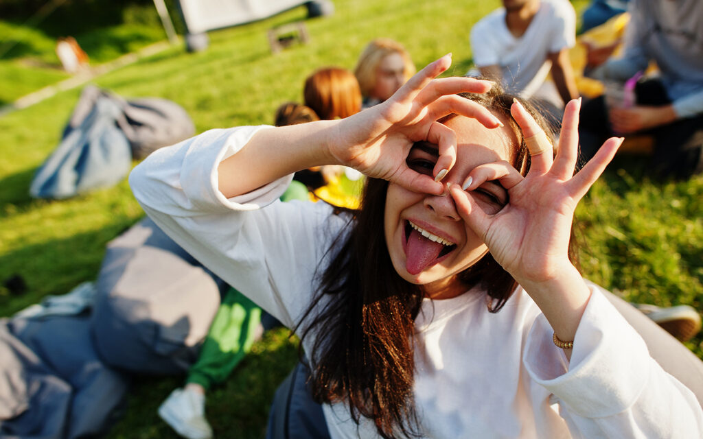 Junges M&auml;dchen schneidet in die Kamera eine fr&ouml;hliche Maske