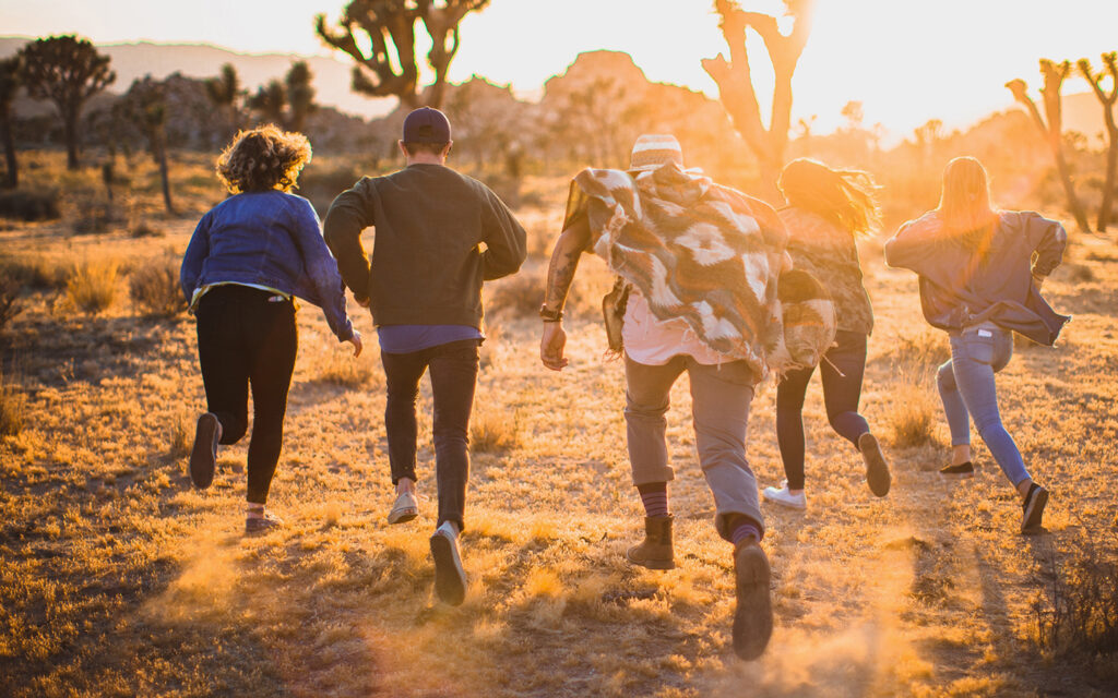 Jugendliche rennen gemeinsam in eine sonnendurchflutete Landschaft hinein