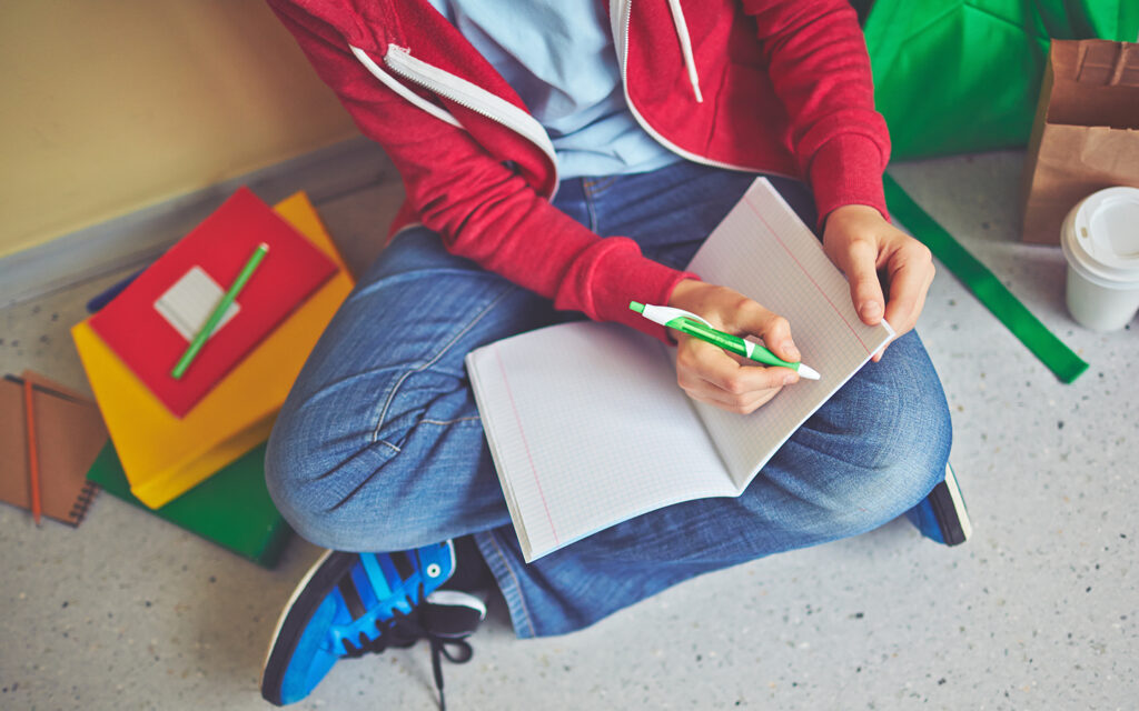 Junge schreibt sich in ein Schulheft einige Notizen