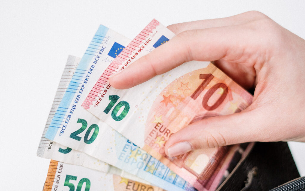 Eine Hand nimmt Euroscheine aus einer Geldtasche.