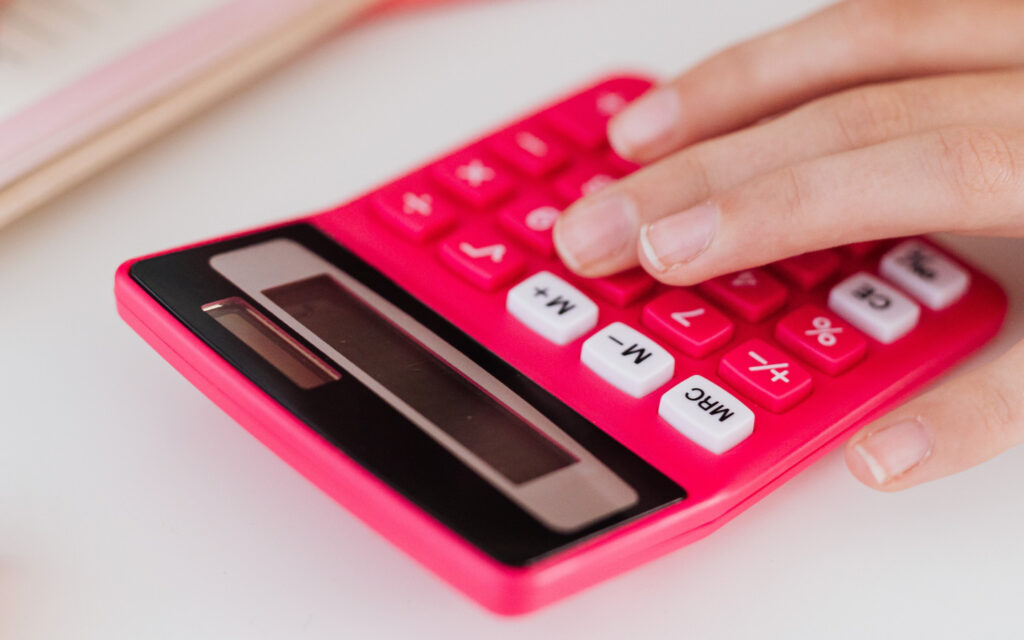 Jemand rechnet etwas auf einem roten Taschenrechner aus.