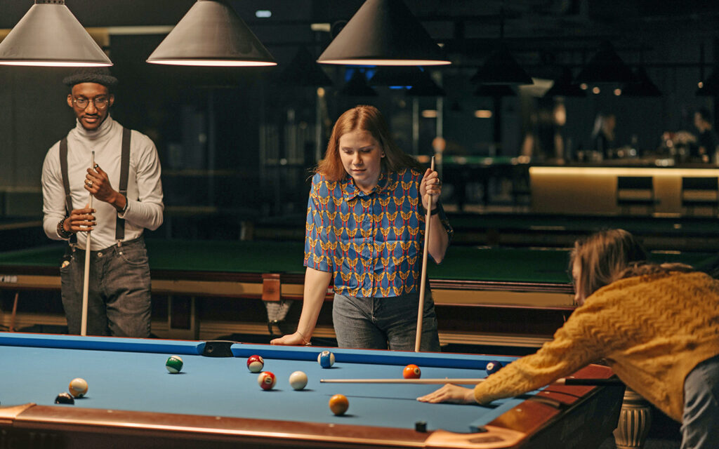 Jugendliche stehen rund um einen Billardtisch