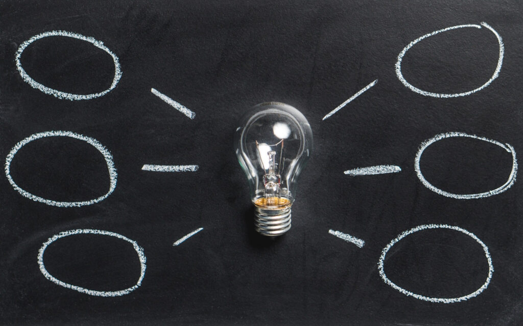 Eine Glühbirne auf schwarzem Hintergrund mit Kreisen rundherum.