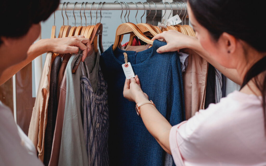Zwei Frauen schauen ein Preisschild von einem Kleidungsstück an.