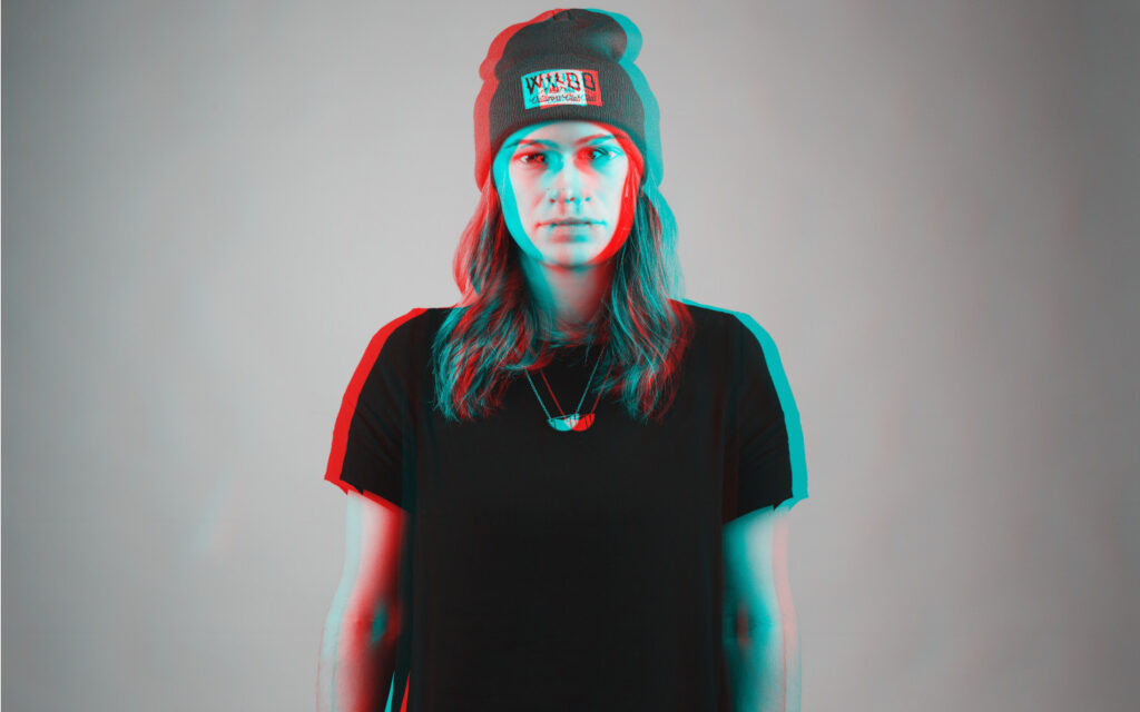 Ein verschwommenes Schwarz-Weiß-Foto einer junge Fraue mit schwarzem T-Shirt und Kappe.