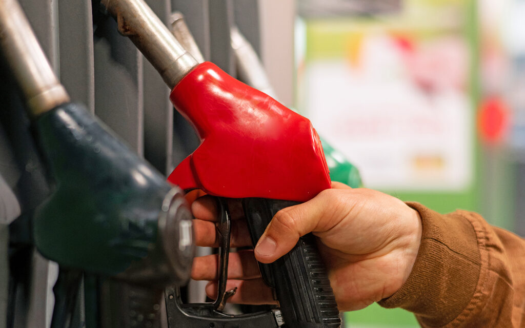 Junger Mann steht an der Zapfsäule